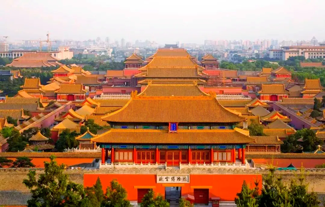 Deep crimson imperial palace walls and golden roof tiles under clear blue skies in Beijing.