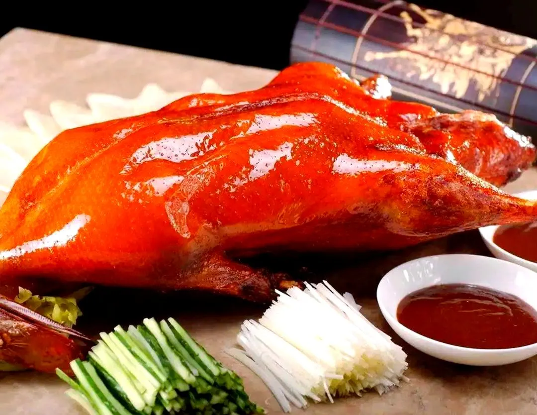 A chef slicing golden-brown crispy roast duck at a table in Beijing.