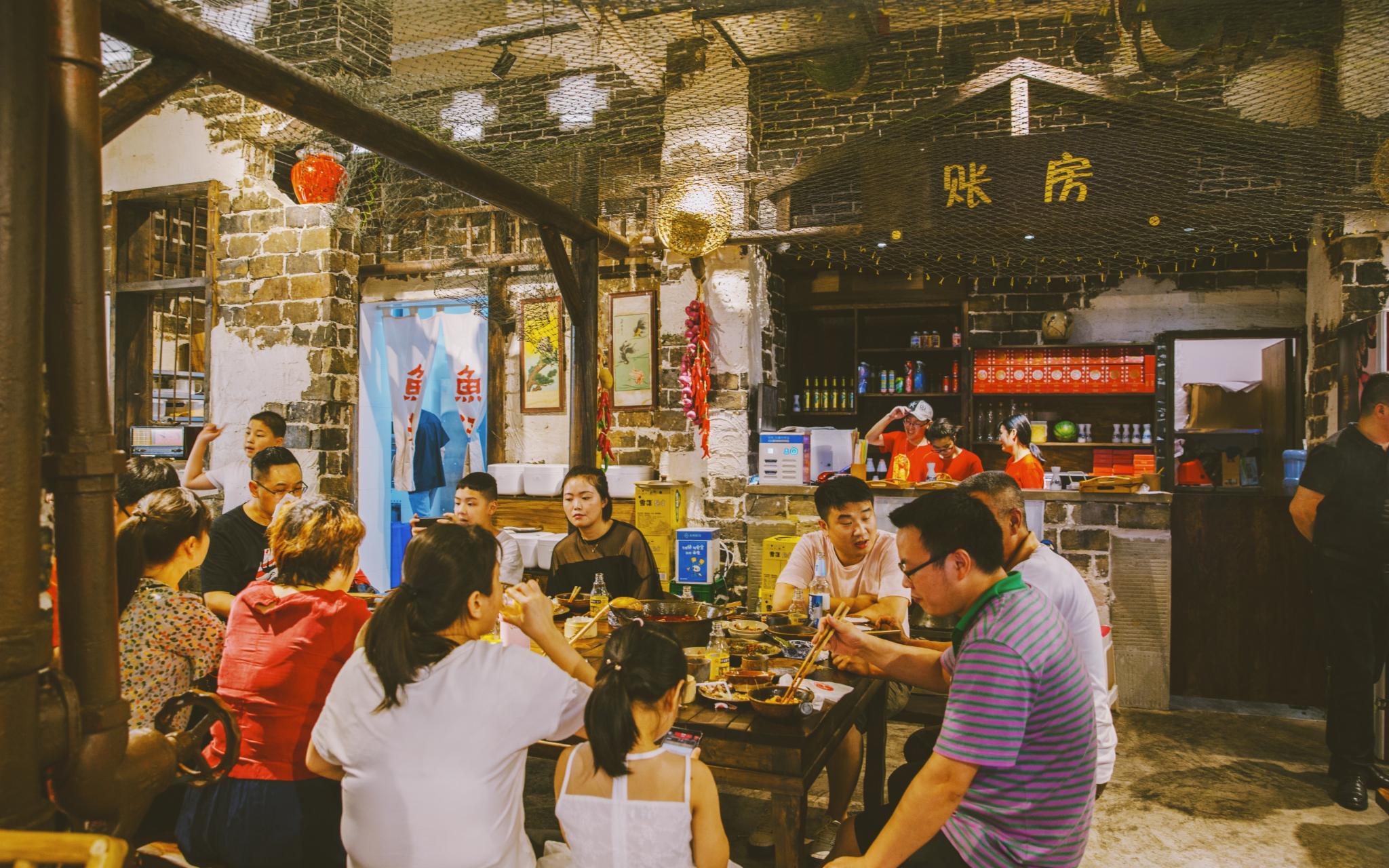 A sizzling metal wok flares with flame as a cook prepares stir-fried noodles in a narrow Chengdu alley.