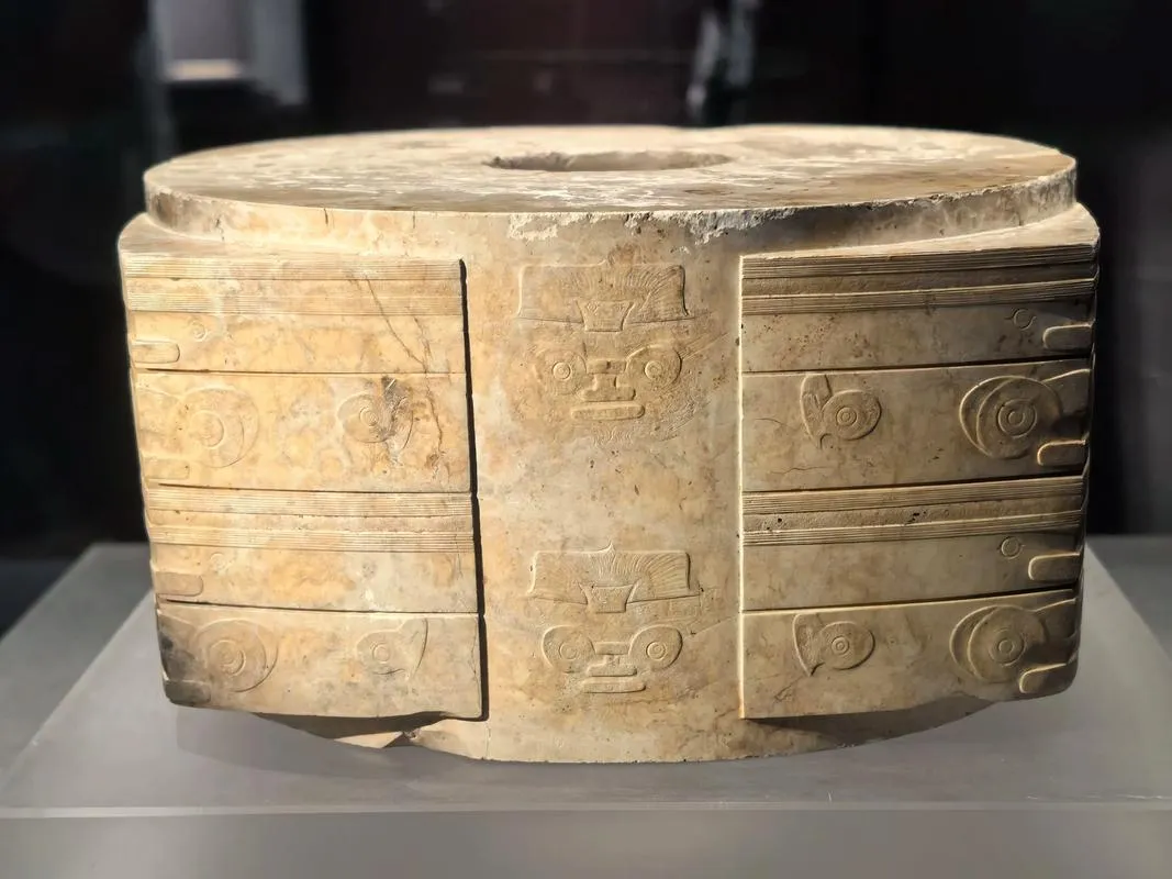 A carved Neolithic jade cong showing the mysterious face of a deity-beast.